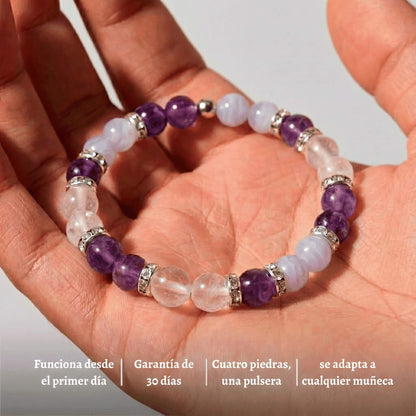 Una mano sostiene la Pulsera Serena - Alivio Natural para la Menopausia, hecha con piedras en tonos morados, azules y transparentes con toques plateados. Equilibra tus hormonas, es ajustable y cuenta con garantía de 30 días.